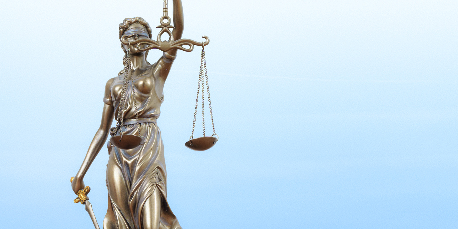 Bronze statue of Lady Justice holding a sword and balance scales against a clear blue sky, symbolizing law, fairness, and impartiality.